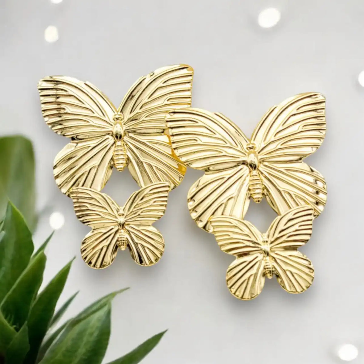 Two pairs of gold-colored butterfly-shaped earrings.