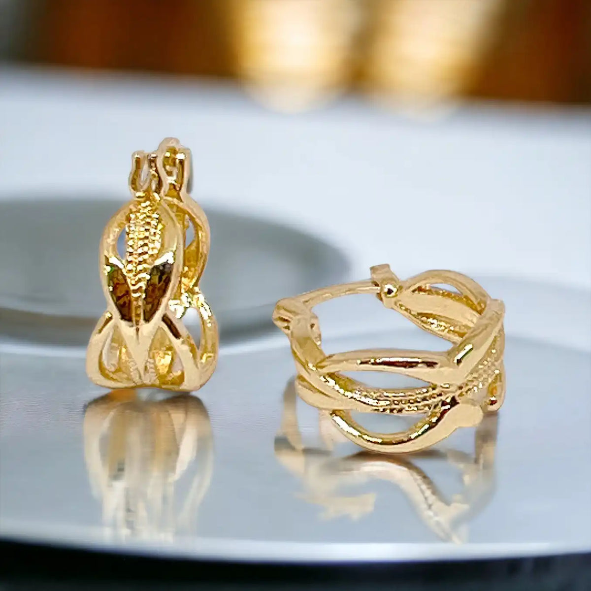 Two gold-colored hoop earrings with intricate, textured designs.